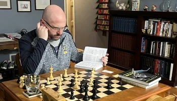 John Hartmann studying at a chessboard