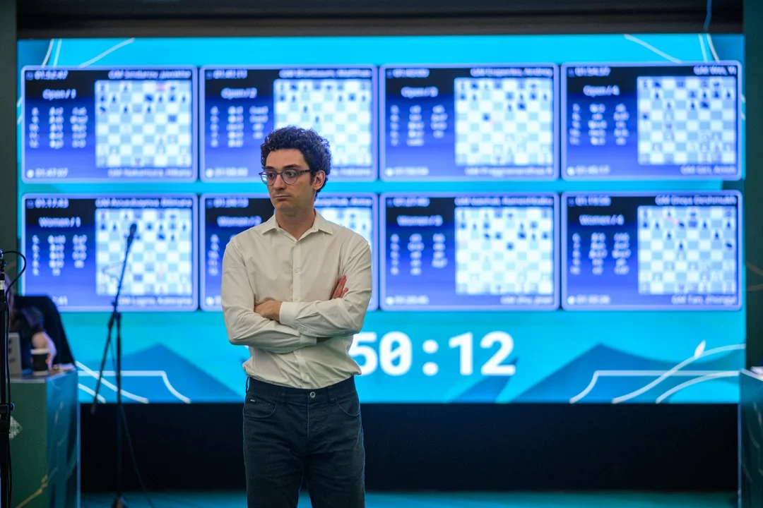 Caruana in front of display boards