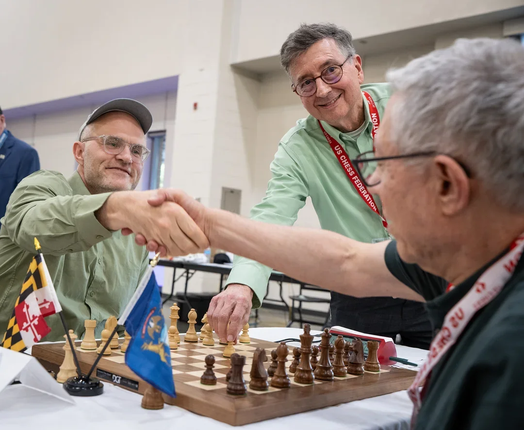 Jesse Kraai (L) and Ariel Levi (MI) shake hands as David Grimaud makes the ceremonial opening move of the Irwin. (Photo by David Llada)