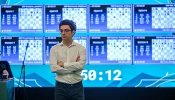 Caruana in front of display boards